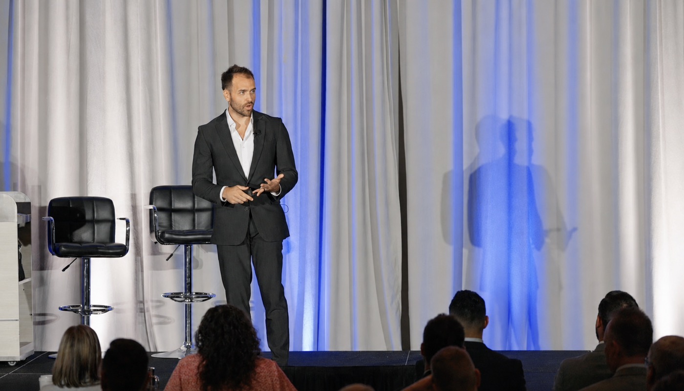Nick Fischer speaking on stage at a chiropractic event