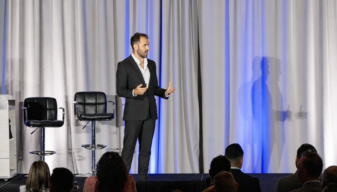 Nick Fischer speaking on stage at a chiropractic event